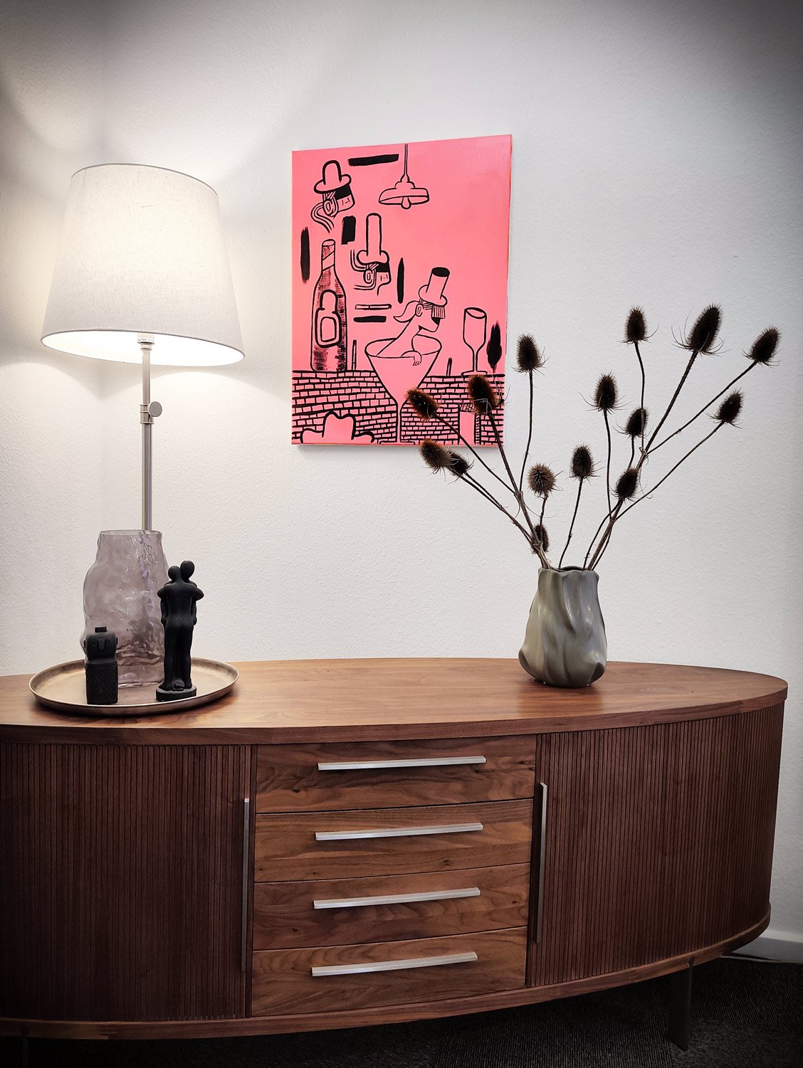 A vibrant, playful, and graphically sharp original painting by acclaimed Danish artist Mormor. Wrapped in an eye-catching, luminous pink hue, the artwork invites the viewer into a whimsical world of nightlife, martini glasses, quirky figures, and shadowy hats. Defined by Mormor's signature bold black contours and pop-art sensibility, the piece captures a nostalgic, dreamlike vibe of late-night hours and cocktail conversations.